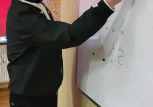 Pan Socjoterapeuta jako prof. Chaos pisze markerem na suchościeralnej tablicy