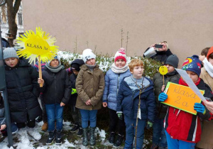 Uczniowie w kurtkach przed szkołą