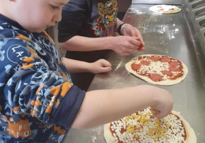 Dzieci nakładają dodatki na placki pizzy