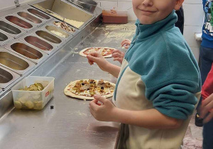 uczeń nakłada na spód od pizzy pozostałe składniki