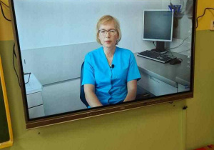 Ekran multimedialny a w nim obraz kobiety - lekarki w niebieskim fartuchu