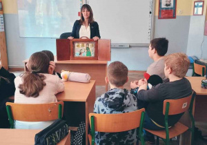 Nauczycielka pokazuje uczniom teatrzykKamishibai