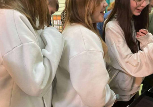 trzy uczennice przy stole kiermaszowym - oglądają i kupuja