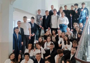Ósmoklasiści pozują do zdjęcia siedząc na schodach
