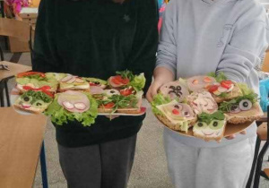 dziewczęta niosą na tacach kolorowe kanapki