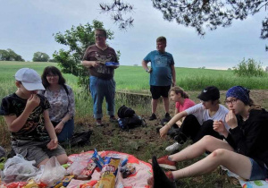 Uczniowie podczas pikniku na trawie pod lasem