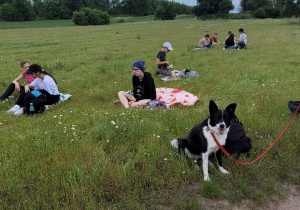 Zielona trawa, a na niej koce i dzieciaki. Na pierwszym planie piaszczysta droga.
