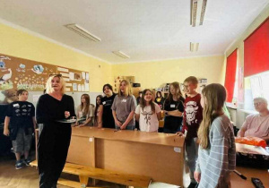 Nauczycielka organizatorka a za nią uczniowie biorący udział w konkursie i widownia