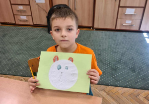 Uczeń trzyma orzed sobą pracę plastyczną