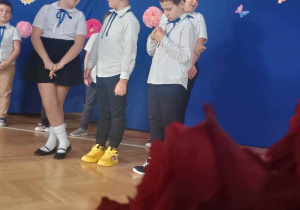 Widok na kwiat i uczniów na tle niebieskiej dekoracji