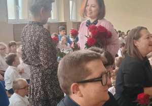 Na pierwszym planie pan pedagog, w tle widać przewodniczącą RR, która wręcza różę nauczycielce