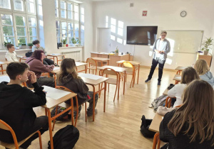 Trener na tle siedzących w ławkach uczniów