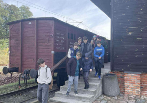 Uczniowie na rampie przy eksponacie bydlęcego wagonu
