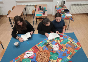 Uczennice przy kolorowo nakrytym stole z otwartymi książkami przed sobą