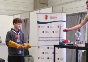 uczeń w gumowych rękawicach trzyma w ręku długi pręt