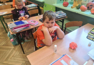 Chłopiec przed wykonaną pracą plastyczną leżącą na ławce