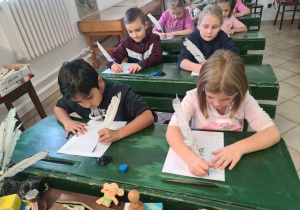 Uczniowie ćwiczą pisanie gęsim piórem
