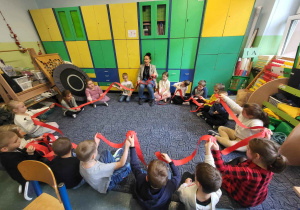 Zajęcia w klasie - uczniowie siedzą w kole, w górze trzymają czerwone karteczki