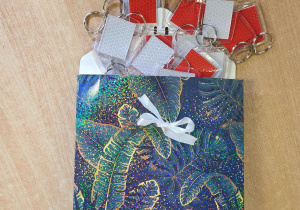 Kolorowa torebka a w niej breloczki z czerwonym odblaskowym tłem