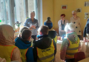 Dzieci z nauczycielką rozmawiają z Seniorami