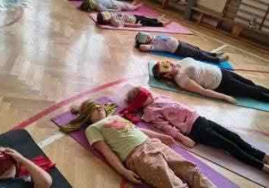 uczniowie leżąna matach w kole głowami do środka