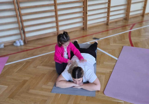 mama leży na karimacie - córka kuca obok - dotyka pleców mamy