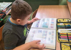 uczeń przegląda z zaciekawieniem klaser ze znaczkami