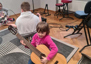 W sali instrumentów muzycznych - dziewczynka gra na gitarze