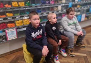 Chłopcy przed ścianą wypełnioną przezroczystymi boksami a w nik klockami Lego