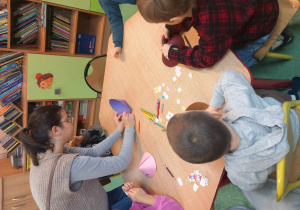 Nauczycielka pomaga dzieciom w wykonaniu pracy plastycznej