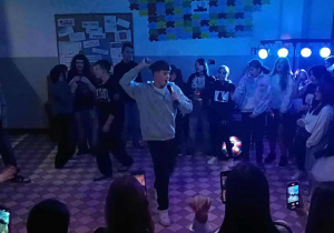 Uczeń z mikrofonem na środku wokół inny uczniowie