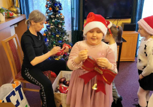 Dziewczynka z czerwoną kokardą w ręku - ozdoba na choinkę