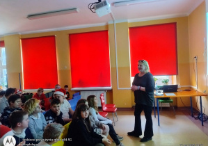 Nauczycielka opowiada, uczniowie na widowni słuchają