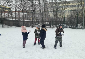 Czworo dzieci bawi się na śniegu