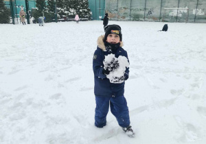 Chłopiec niesie utoczoną ze śniegu kulę