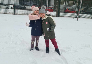 Dziewczynki pozują do zdjęcia na tle ośnieżonego boiska szkolnego