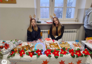 Uczennice przy swoim stoisku - uśmiechem zachęcaja do zakupów