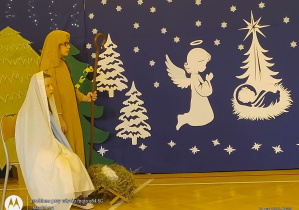 Na tle świątecznej dekoracji uczniowie jako Józef i Maryja z Dzieciątkiem