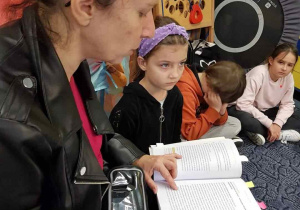 Nauczycielka czyta dzieciom tekst z książki