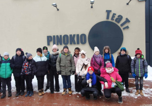Uczniowie na tle logo Teatru Pinokio