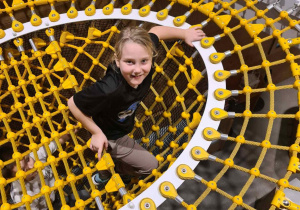 Chłopiec wspina się po żółtej siatce