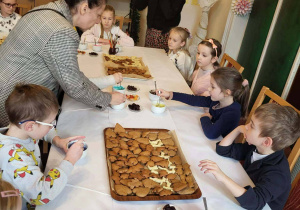 uczniowie ozdabiają pierniczki pod okiem swojej nauczycielki