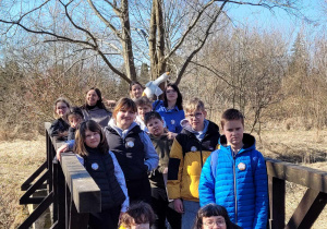 Uczestnicy rajdu stoją na tle wiosennego drzewa, błękitnego nieba.