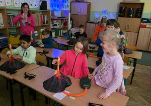 Uczniowie wykonują eksperyment siedząc w swoich ławkach