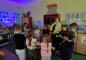 Uczniowie i trenerka stoją w kole na dywanie