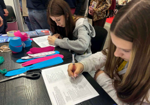 Dziewczyny pochylone nad kartką - wypełniają ankietę lub test