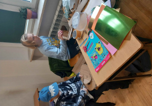 Dwoje uczniów przy biurku na którym przygotowano kolorowe materiały plastyczne