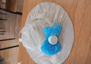 Kapelusz w białej folii z niebieską kokardką i środkiem z plastikowej nakrętki