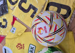 Żółte koszulki i kolorowe piłki jakie otrzymali dla szkoły uczestnicy turnieju.