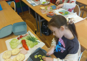 Uczniowie przy swoich ławkach przygotowują produkty do kolorowych, wiosennych kanapek